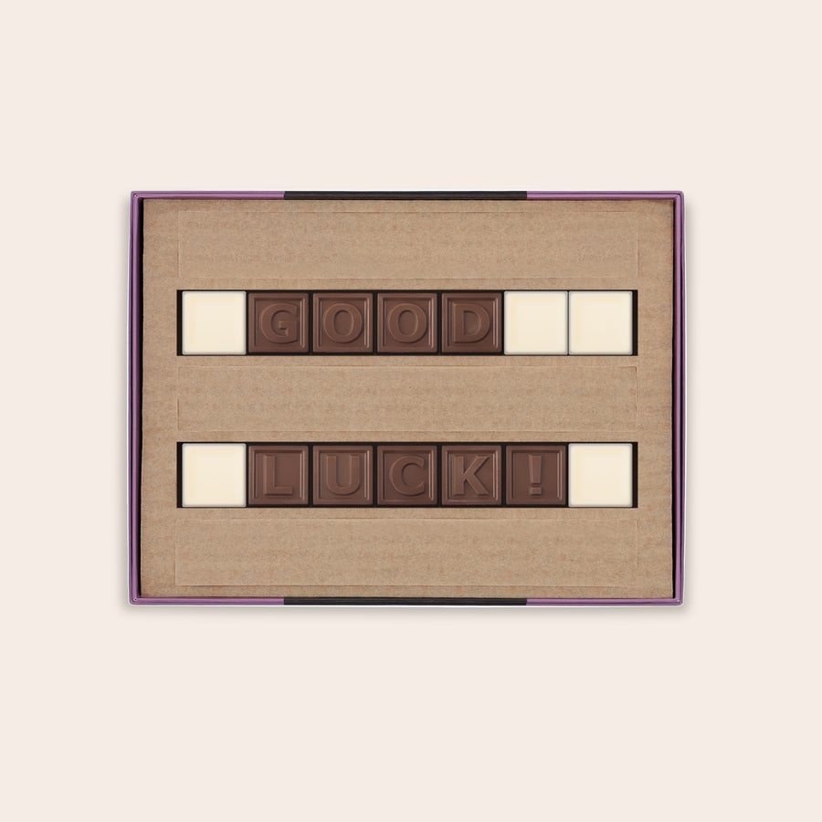 A personalized chocolate telegram with milk chocolate letters spelling GOOD LUCK and white chocolate spacers